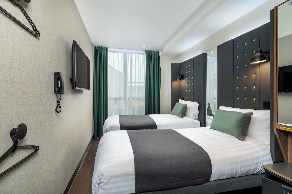Ett hotellrum med två sängar, en TV, en telefon och en spegel.