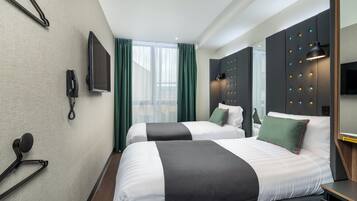 Habitación de hotel con dos camas, televisión, teléfono y espejo.