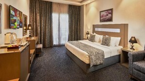 Habitación de hotel con cama, escritorio, silla, mesita de noche y ventana con cortinas.
