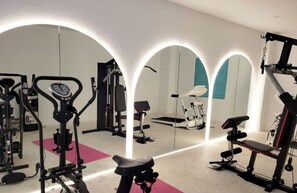 Ein Fitnessstudio mit verschiedenen Trainingsgeräten, darunter Laufband, Crosstrainer und Kraftgeräte.