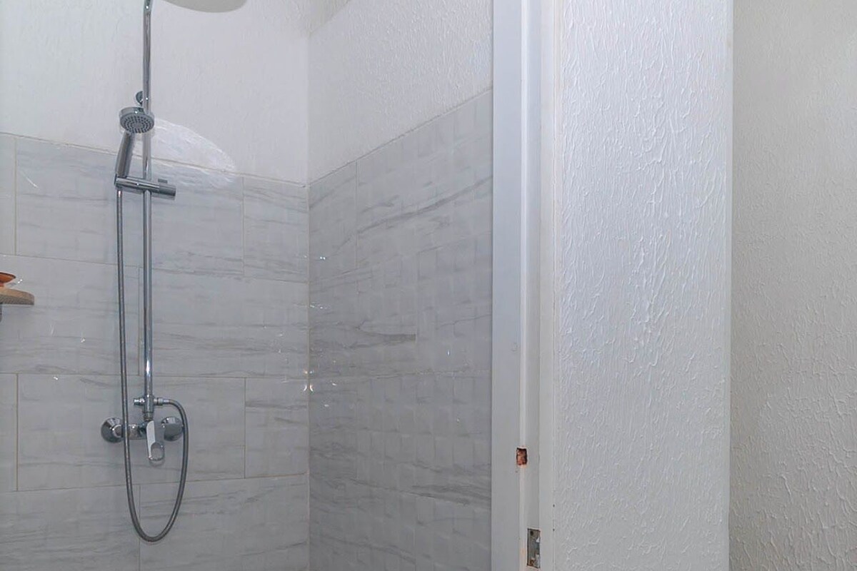 Eine Dusche mit Handbrause und Wandarmatur.