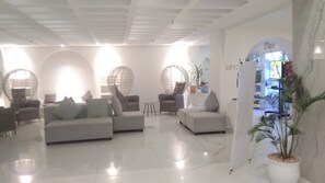A modern hotel lobby with sofas, a reception desk, and a plant. - Loccal Collection Hotel Labuan Bajo (Labuan Bajo)