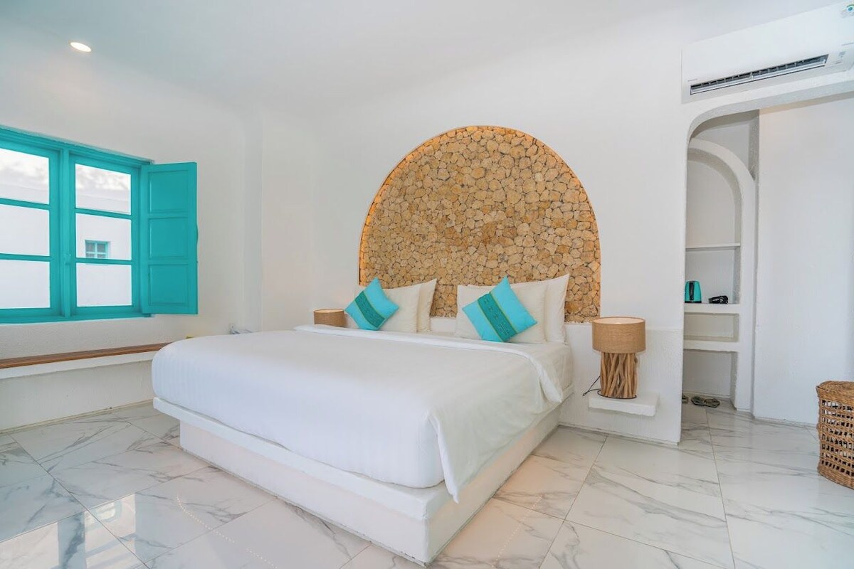 Ein Schlafzimmer mit einem Bett, einer runden Wanddekoration, einem Fenster mit blauen Rollläden und einer weißen Klimaanlage.