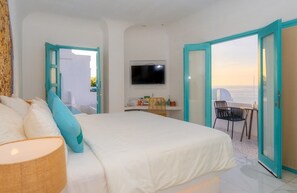 Una camera da letto con un letto, una televisione, una scrivania con una sedia e un balcone con vista.
