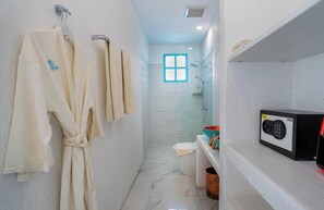 Ein Badezimmer mit Dusche, Toilette und Handtuchhalter mit Bademänteln.