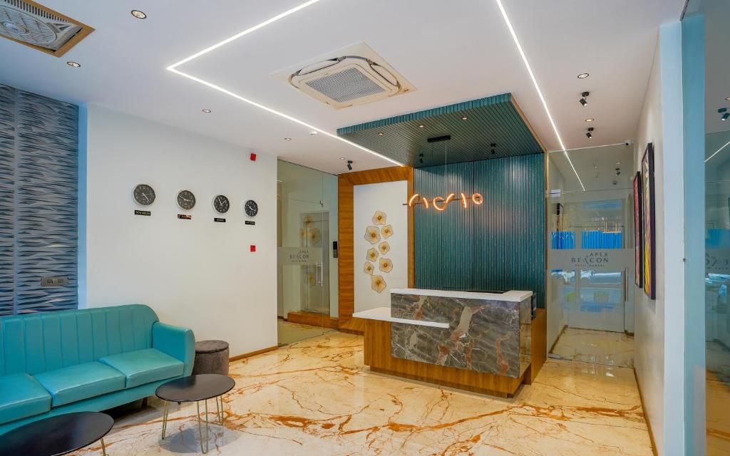 A reception area with a teal sofa, marble flooring, and a neon sign.