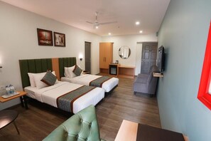 A hotel room with two beds, a green chair, a small table, a TV, a mirror, and a ceiling fan. - Apex Beacon Hotel Andheri Mumbai (Mumbai)