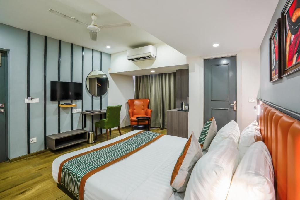 A hotel room with a bed, a desk, a chair, a television, and an air conditioning unit.