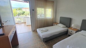 Habitación de hotel con dos camas, un escritorio y un balcón.