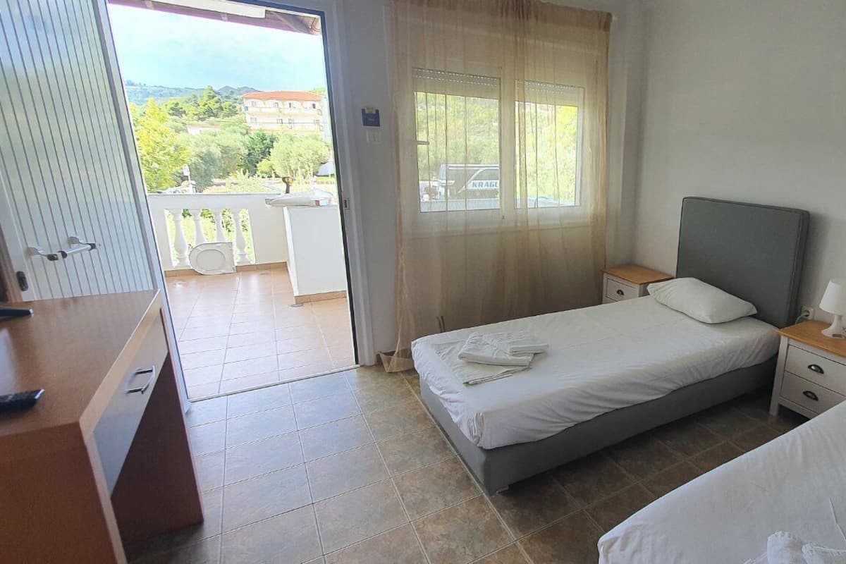 A hotel room with two beds, a desk, and a balcony.