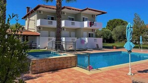 A two-story building with a swimming pool, balconies, and a palm tree. - Villa Ilios Hotel (Kassandra)