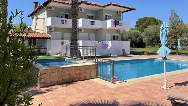 Un edificio de varios pisos con balcones, piscina y una palmera.