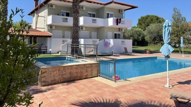 A multi-story building with balconies, a swimming pool, and a palm tree. - Villa Ilios Hotel (Kassandra)