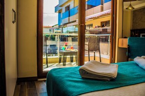 Ein Hotelzimmer mit Bett, Balkonblick und einem Sessel.