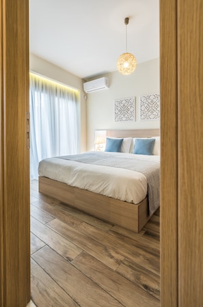 A bedroom with a wooden bed, a hanging light fixture, and a window with curtains. - Lemar (Hersonissos)