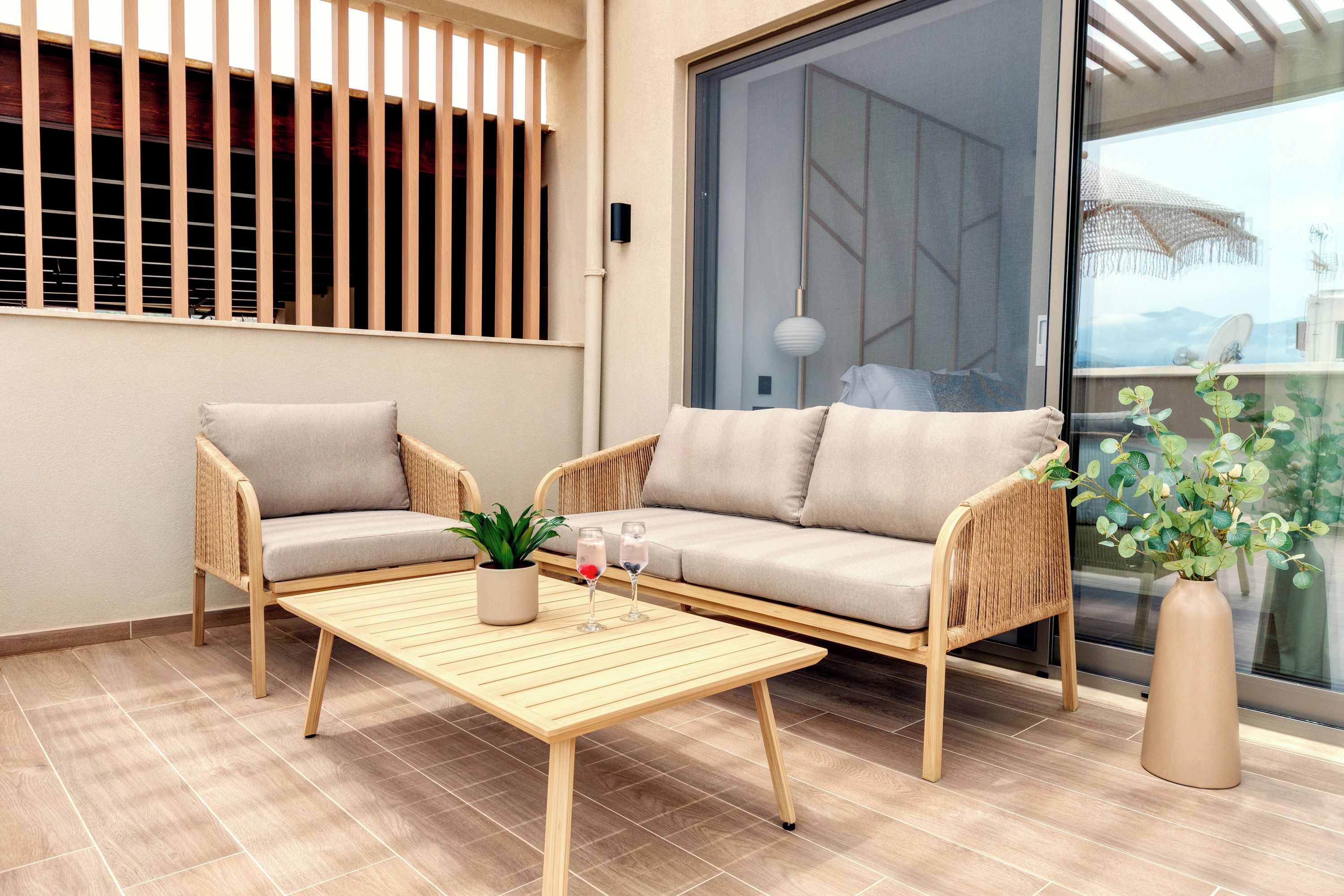 A modern living room with a sofa, two armchairs, a coffee table, and a potted plant.