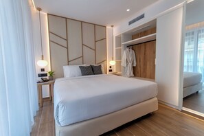 A modern hotel room with a large bed, bedside tables, a robe hanging, and a wardrobe. - Lemar (Hersonissos)