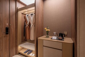 A compact bathroom with a shower, a vanity with a mirror, and a small shelf with slippers. - Orange Crystal Hotel Suzhou East Railway Station (Suzhou)