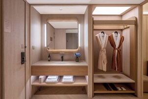 Un baño moderno con un espejo grande, un lavabo y un tendedero para albornoces.