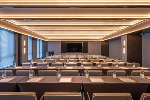 A conference room with rows of tables, chairs, and water bottles, featuring a modern ceiling design and a central screen. - Orange Crystal Hotel Suzhou East Railway Station (Suzhou)
