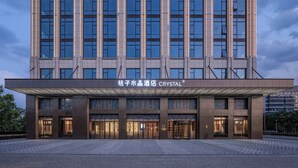 A modern hotel building with a large entrance, multiple floors, and a prominent signage. - Orange Crystal Hotel Suzhou East Railway Station (Suzhou)