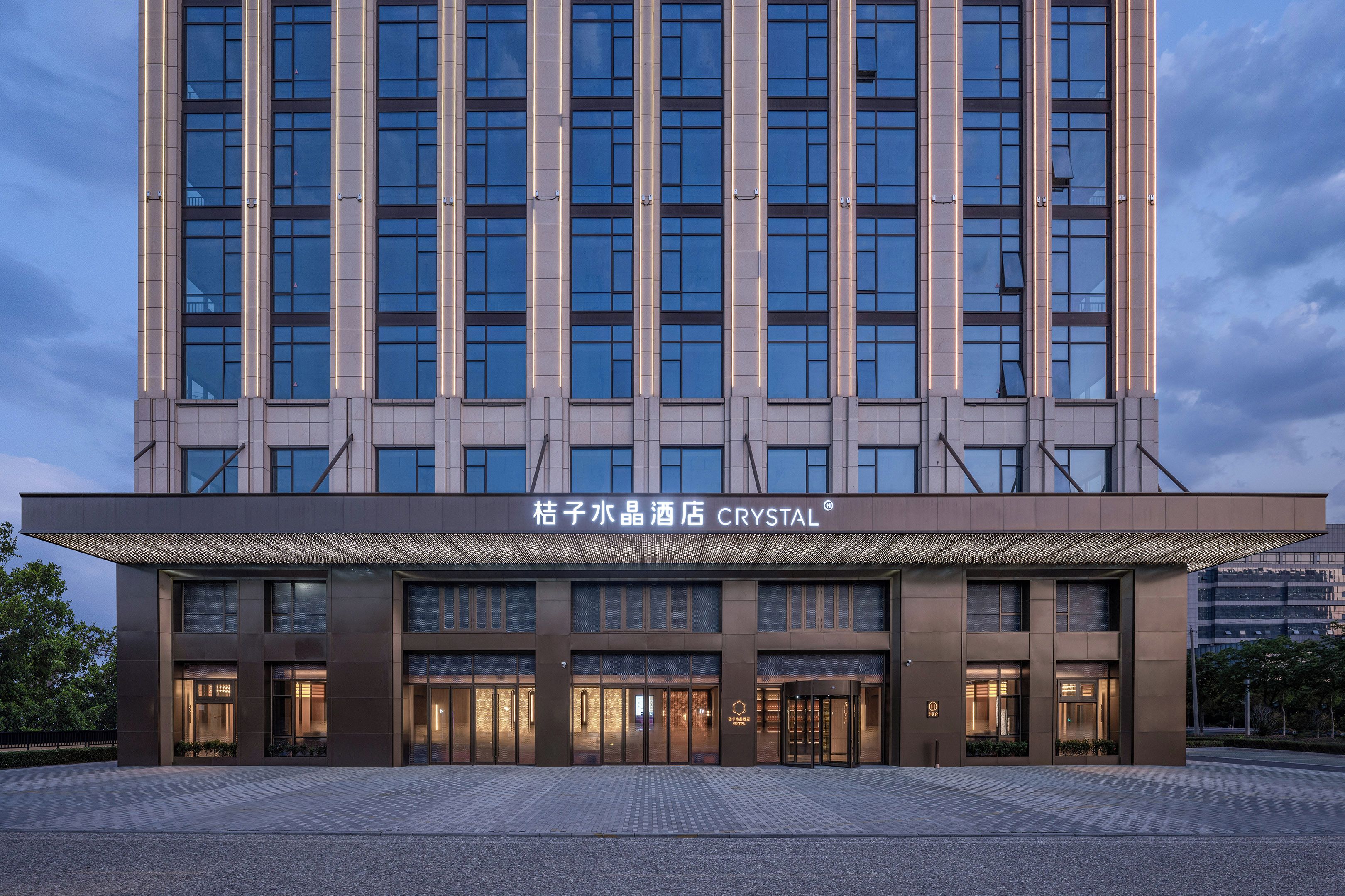 Un moderno edificio de hotel con una entrada amplia, varios pisos y señalización destacada.