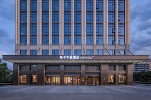 A modern hotel building with a large entrance, multiple floors, and a prominent signage. - Orange Crystal Hotel Suzhou East Railway Station (Suzhou)