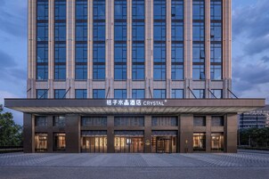 Un moderno edificio de hotel con una entrada amplia, varios pisos y señalización destacada.