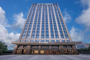 A tall, modern hotel building with a clear sky and clouds. - Orange Crystal Hotel Suzhou East Railway Station (Suzhou)