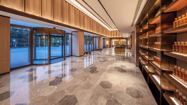 A modern hotel lobby with a polished floor, wooden paneling, glass doors, and shelves with bottles. - Orange Crystal Hotel Suzhou East Railway Station (Suzhou)