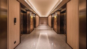 A modern elevator lobby with a polished floor, wooden paneling, and illuminated ceiling lights. - Orange Crystal Hotel Suzhou East Railway Station (Suzhou)