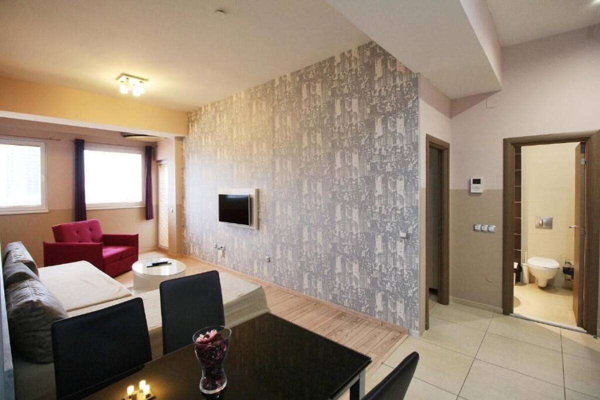 Una sala de estar moderna con un sofá, sillas, una mesa de centro y un televisor montado en la pared.