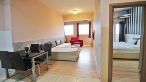 Una habitación de hotel con una cama, un sofá, una mesa de comedor con sillas y una silla roja.