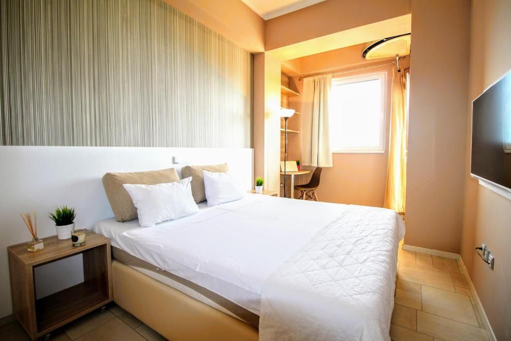 A hotel room with a bed, bedside table, lamp, and a TV.