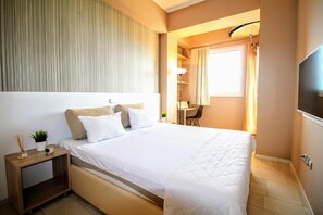 Una habitación de hotel con cama, mesita de noche, lámpara y televisión.
