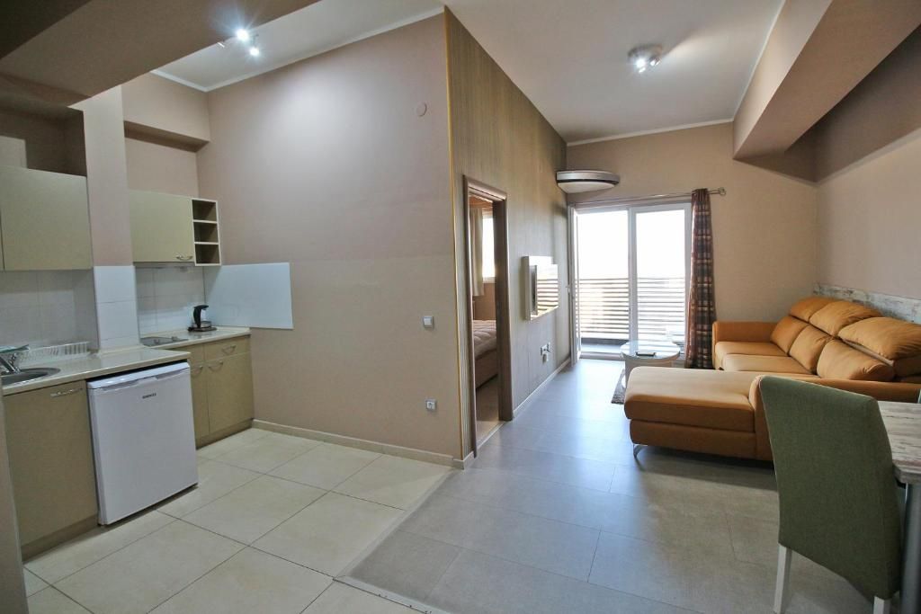 Una cucina moderna con lavastoviglie, una zona pranzo con tavolo e sedie, e un soggiorno con divano.