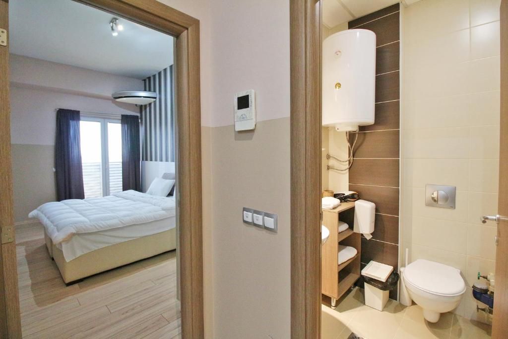 A hotel room with a bed, a bathroom with a toilet, and a shower.