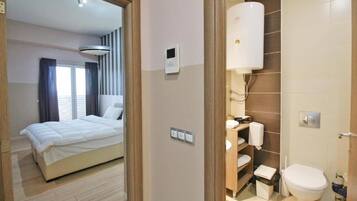 A hotel room with a bed, a bathroom with a toilet, and a shower.