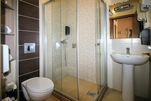 A bathroom with a glass-enclosed shower, a toilet, and a sink.