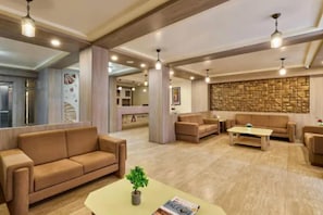 Un vestíbulo espacioso con un sofá color beige, una mesita de centro y un muro decorativo.