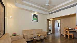 Un salon avec un canapé, une table basse et un tableau au mur. Il y a également un coin repas avec une chaise et une table.