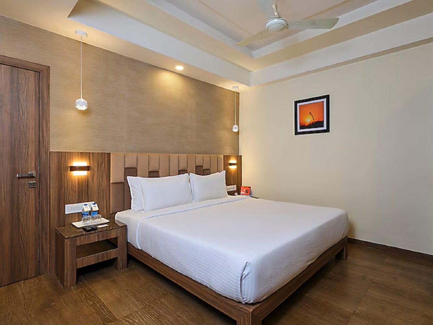 A bedroom with a wooden bed, nightstands, a ceiling fan, and a wall-mounted light fixture.