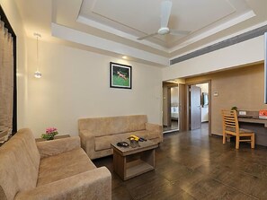 Ein Wohnzimmer mit Sofa, Couchtisch und einem Bild an der Wand. Es gibt einen Essbereich mit einem Stuhl und einem Tisch.