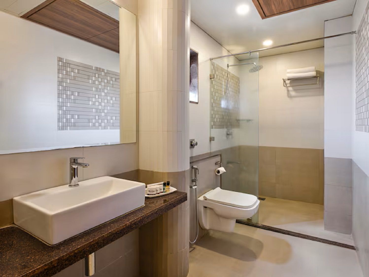 A modern bathroom with a large sink, toilet, and glass-enclosed shower.