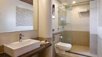 Een moderne badkamer met een groot wastafelmeubel, toilet en een douchecabine met glazen wanden.
