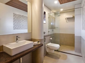 Un baño moderno con un lavamanos grande, inodoro y ducha con mampara de vidrio.
