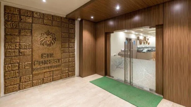 Un espace d’accueil avec un mur en pierre, un emblème représentant un lion et un tapis vert.