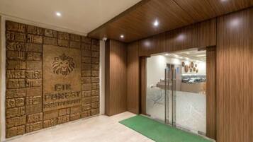 Una zona de recepción con pared de piedra, un emblema de león y un felpudo verde.