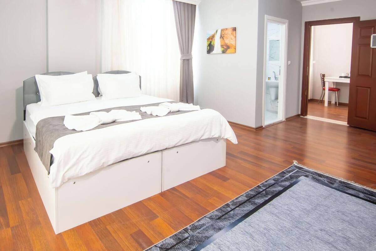 Ein Schlafzimmer mit Bett, Holzboden, einer Tür und einem Fenster.