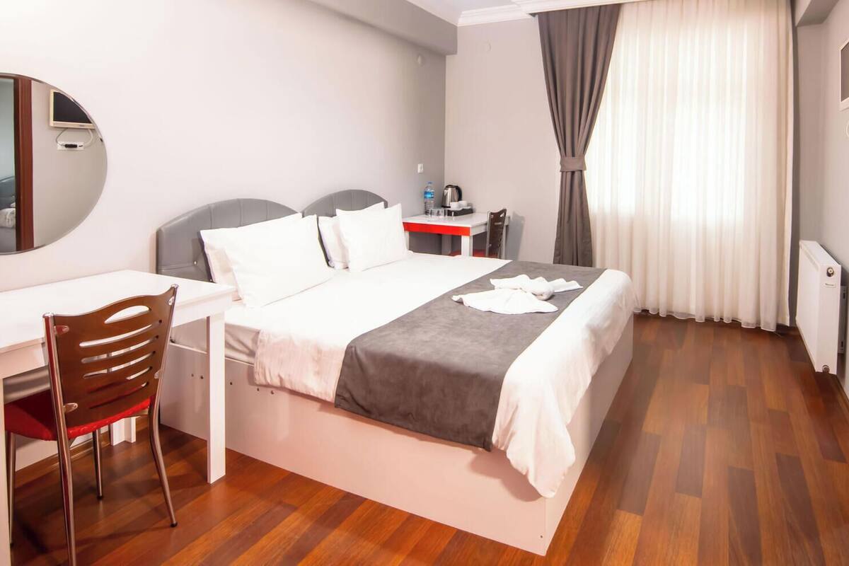 Ein Hotelzimmer mit Bett, Schreibtisch, Stuhl und Spiegel.